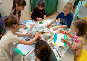 Dzieci siedzą przy stoliku i malują marcową pogodę.