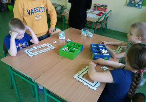 Dzieci siedzą przy stoliku i budują trasę z puzzli dla robota.