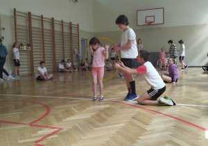 Sala gimnastyczna. Dzieci biorą udział zawodach sportowych - wyścigi rzędów.