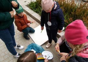 Ulica Włókiennicza. Uczestnicy malują obraz na płótnie położonym na chodniku.