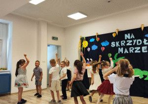 Sala gimnastyczna. Występ z okazji zakończenia roku. W tle dekoracja.