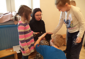 Dziewczynka z grupy Biedronek głaszcza kota, który leży na kolanach u Pani z Fundacji "Kocia Mama"