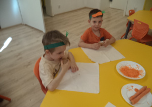 Chłopcy jedzą babeczki z marchewki.