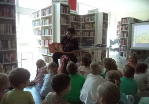 Pan bibliotekarz czyta i pokazuje dzieciom książkę o Pippi Pńczoszance.