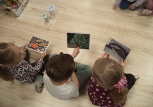Na zdjęciu widoczne są dzieci, które trzymają w ręku kartki, z różnymi zdrowymi produktami spożywczymi.