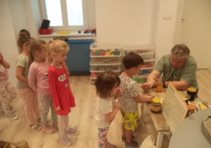 Na zdjęciu są dzieci, które stoją w kolejce do degustaci miodów.