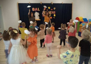Na zdjęciu widoczne są dzieci wraz z Panią Anią i Panią Sylwią. Dzieci i dorośli wspólnie tańczą, trzymając w ręku papierowe parasolki.