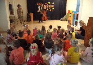 Na zdjęciu widoczne są dzieci z naszego przedszkola oraz Państwo, którzy prowadzili wrześniową audycję muzyczną. Pan gra na instrumencie (kontrabas).