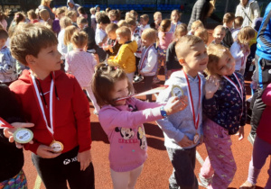 Boisko szkolne. Dzieci z grupy Biedronek pozują z medalami.