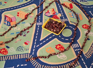 Na dywanie znajduje się pojemnik z darami jesieni - kasztanami, szyszkami, orzechami. Dookoła niego ułożona jest ścieżka z kasztanów.