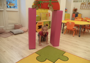 Dziewczynka przechodzi na czworaka przez bramę udekorowaną ziemniakami.