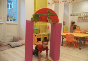 Chłopczyk przechodzi na czworaka przez bramę udekorowaną ziemniakami.