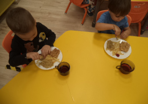 Dwóch chłopców je obiad - rybę z frytkami.