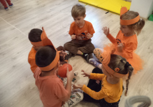 Grupa dzieci w kole i podaje sobie dynię.