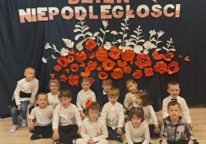 Dzieci z grupy Biedronek pozują na tle dekoracji z okazji Dnia Niepoległości.