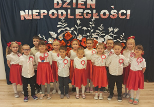 Dzieci z grupy Motylków pozują na tle dekoracji z okazji Dnia Niepoległości.