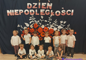 Dzieci z grupy Sówek pozują na tle dekoracji z okazji Dnia Niepoległości.