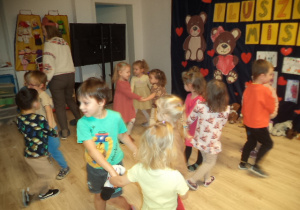 Dzieci tańczą w parach na tle dekoracji z okazji Dnia Pluszowego MIsia.