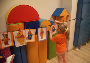 Dziewczynka przyczepiaa do sznurka ilustrację misia Paddigntona.