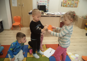 Na zdjęciu widać czworo dzieci, które wspólnie świętują Andrzejki. Chłopiec na zdjęciu przebija papierowe serce, na którym ukryte były imiona dziewczynek.