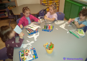 Na zdjęciu widoczne są dzieci, które wycinają kredkę z szablonu, usprawniając jednocześnie motorykę małą, koordynację oko-ręka oraz precyzje ruchów.