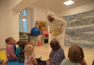 Aktor ubrany w strój niedźwiedzia zwraca się do dzieci.