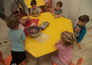 Dzieci przyglądają się jak pani wyrabia ciasto.