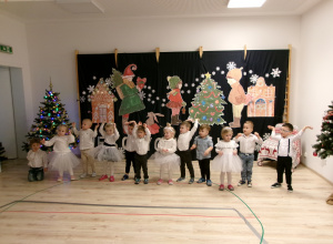 Elegancko ubrane dzieci występuja na tle świątecznej dekoracji.