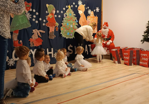 Na zdjęciu widać jak dzieci dostają prezenty od Mikołaja.