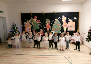 Na zdjęciu widać dzieci, które kucają na tle świątecznej dekoracji.