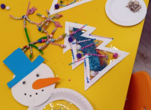 Na zdjęciu widać prace dzieci - bałwanki i choinki zrobione z papierowych talerzyków i folii.