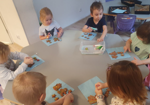 Na zdjęciu widać dzieci, które dekorują pierniczki.