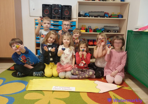 Na zdjęciu widoczne są dzieci z grupy Biedronek, które trzymają w ręku własnoręcznie wykonaną kredkę swiecową w kształcie serca.