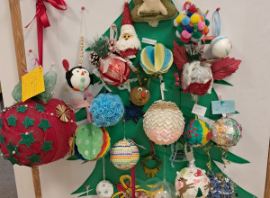 Na zdjęciu widać papierową choinkę, do której są przyczepione różne bombki zrobione przez dzieci.