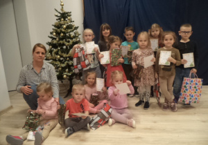 Na zdjęciu widać panią i dieci, które pozują do zdjęcia z dyplomami i nagrodami.