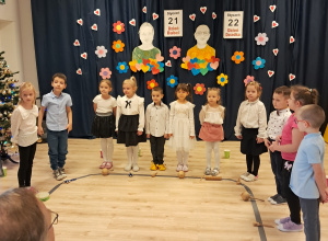 Na zdjęciu widać elegancko ubrane dzieci stojące w półkolu. Przed nimi leżą instrumenty.