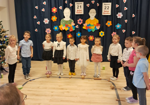 Na zdjęciu widać elegancko ubrane dzieci stojące w półkolu. Przed nimi leżą instrumenty.