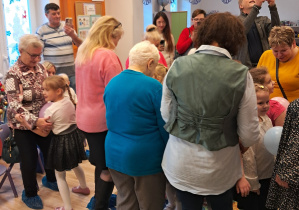 Na zdjęciu widać babcie i dziadków i dzieci tańczących z balonami.