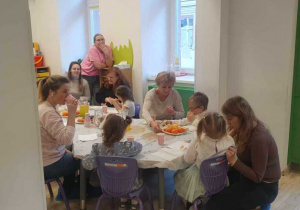 Na zdjęciu widać dzieci i dziadków częstujących się przygotowanym poczęstunkiem.