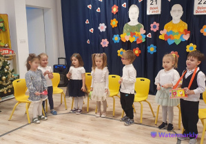 Na zdjęciu widać elegancko ubrane dzieci trzymające różne instrumenty.