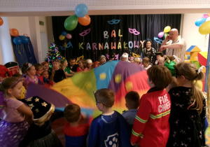 Dzieci przebrane w stroje bawią się chustą animacyjną.