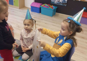 Na zdjęciu widać dziewczynkę rozdającą cukierki.