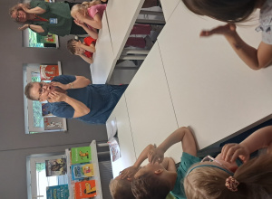 Na zdjęciu widać dzieci znajdujące się w bibliotece naśladujące Panią.