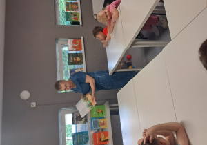 Na zdjęciu widać jak dzieci słuchają Pani, która czyta książkę.