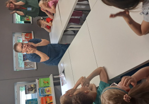 Na zdjęciu widać dzieci znajdujące się w bibliotece naśladujące Panią.