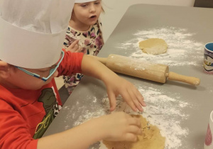 Chłopiec i dziewczynka rozgniatają ciasto palcami.