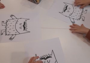 Na zdjęciu widać dzieci kolorujące potworki.