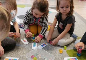 Dziewczynki ustawiają plastikowe foremki do lodu zgodnie układem klocków z obrazka.