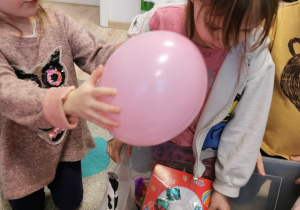 Dziewczynki wyciągają balony oraz inne rzeczy z pudełka, np. szklane kamyczki.