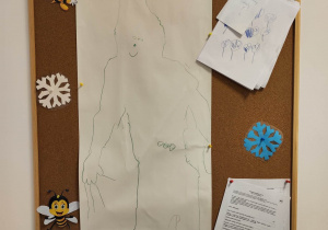 Tablica z pracami dzieci. Na dużym, prostokątnym papierze dzieci (praca grupowa) narysowały szkic Ufoludka.